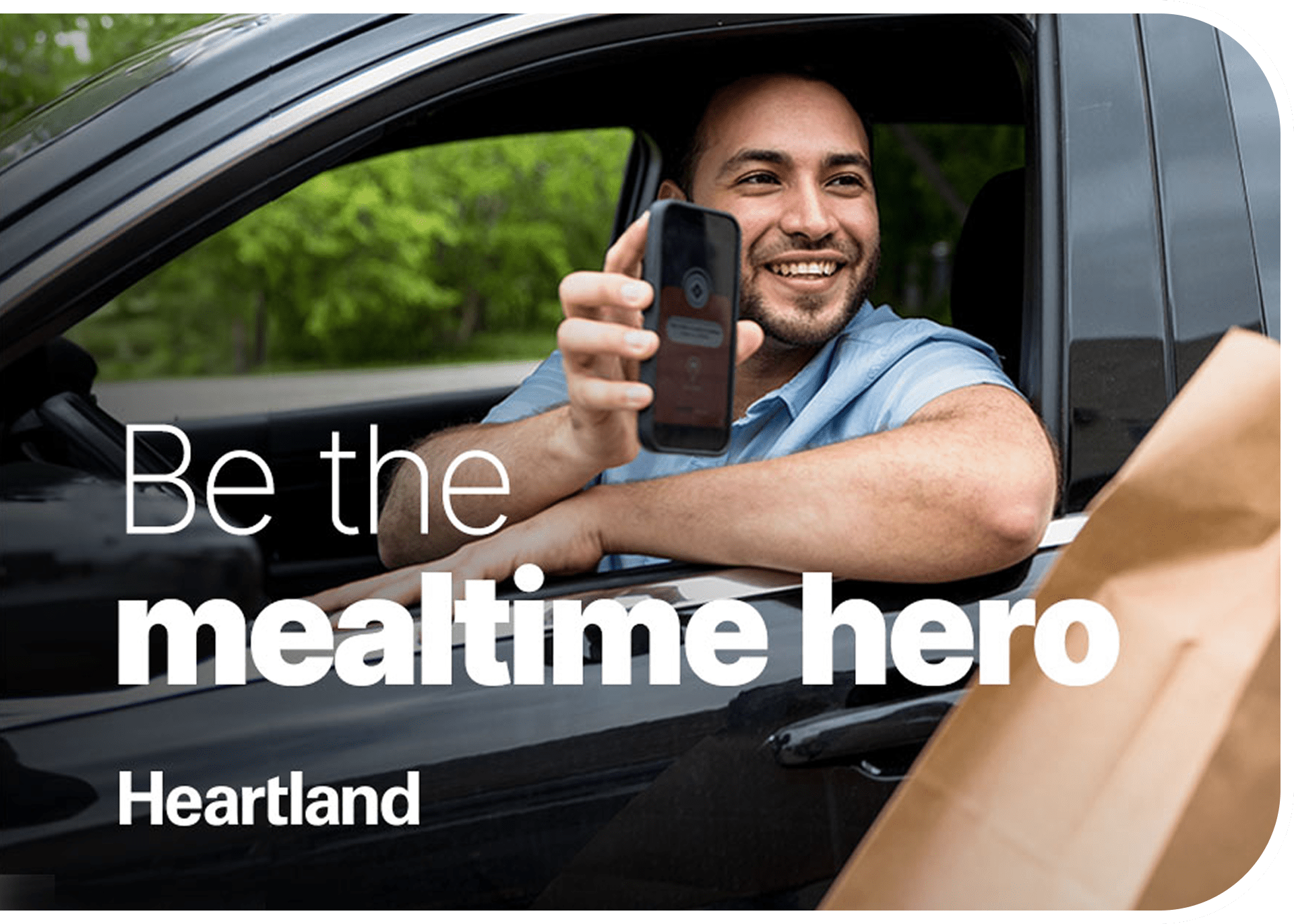 Man in car holding a phone, smiling.